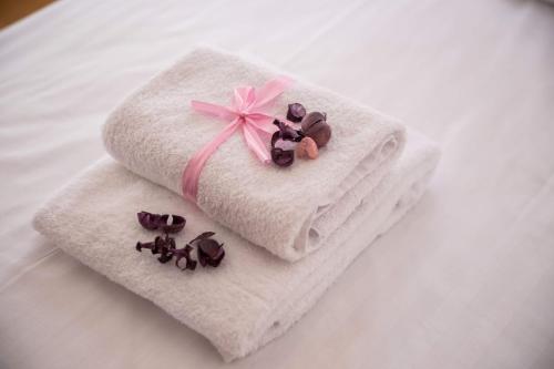 a white towel with a pink bow and some chocolates at Apartments Villa Maria in Crikvenica
