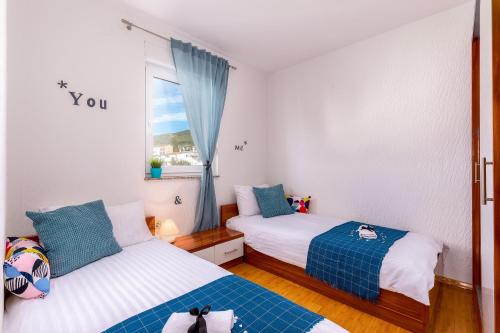 two beds in a small room with a window at Apartments Villa Maria in Crikvenica