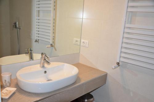 uma casa de banho com um lavatório branco e um espelho. em B&B La Via dell'Ambra em Due Carrare