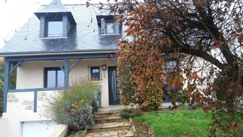 une maison blanche avec une porte bleue et un arbre dans l'établissement Jo Masson, à Saint-Aubin-dʼAubigné