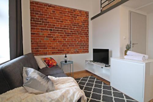 a living room with a couch and a brick wall at Aparthotel Tectum TectumApartments in Wrocław