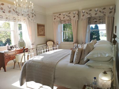 a bedroom with a bed and a desk and windows at Cleatham Hall in Manton