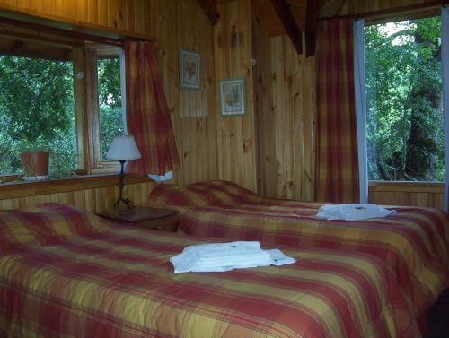 two beds in a room with wooden walls and windows at Cabañas Temporada in San Martín de los Andes