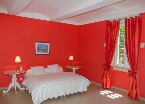 Dormitorio rojo con cama y ventana en La Moutière, en Colonzelle