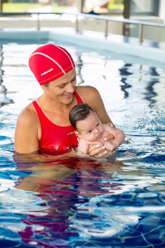 a woman holding a baby in a swimming pool at WISH Aqua&SPA Resort in Vishenki