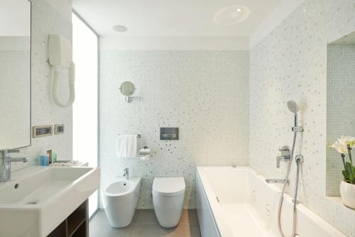 a bathroom with two sinks and a tub and a toilet at Hotel Belvedere in Bellagio