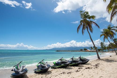 une rangée de bateaux sur une plage avec un palmier dans l'établissement Hotel Arawak Beach Resort, au Gosier