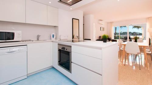 a white kitchen with white cabinets and a dining room at Apartamento Blue Carabela in Alcudia