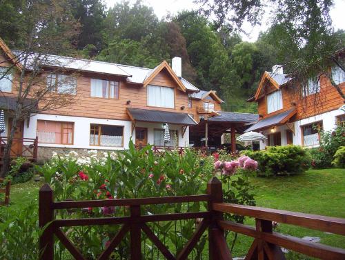 a wooden house with a fence in a yard at Cabañas Temporada in San Martín de los Andes