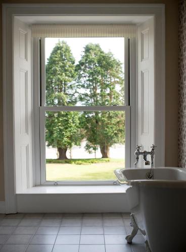 a bathroom with a window with a tub and a sink at Mansion House Llansteffan in Carmarthen