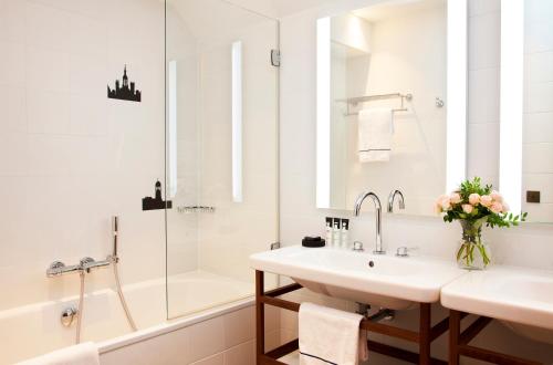 a white bathroom with a sink and a shower at Relais de Chambord - Small Luxury Hotels of the World in Chambord