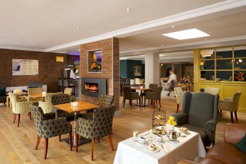 a restaurant with tables and chairs and a fireplace at Springhill Hotel Kilkenny in Kilkenny