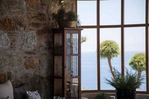 a room with a large window with plants on a shelf at Seaside A Lifestyle Resort - Adults Only in Agia Pelagia