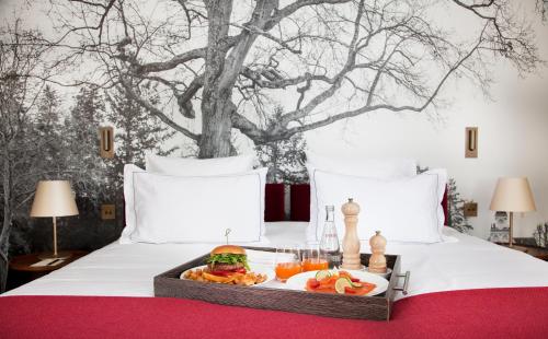a tray with a sandwich and fruit on a bed at Relais de Chambord, a Small Luxury Hotels of the World in Chambord