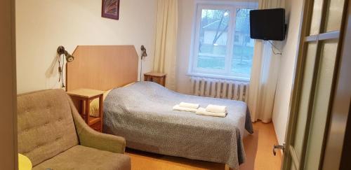 a bedroom with a bed and a chair and a television at Velga in Vilnius