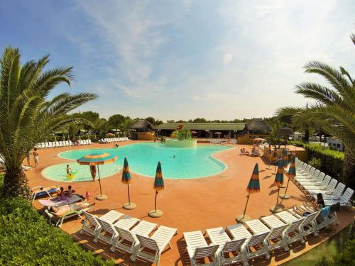 a large swimming pool with chairs and umbrellas at Happy Camp mobile homes in Camping Village Free Time in Marina di Bibbona