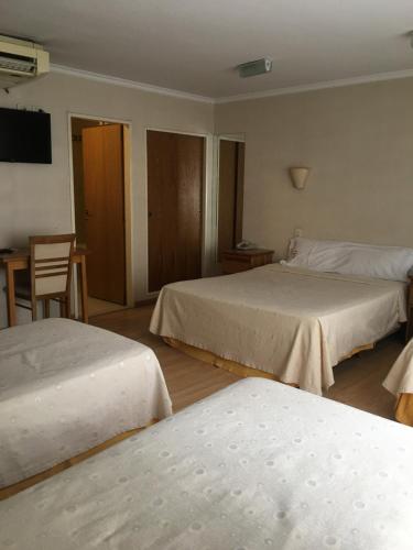 a hotel room with two beds and a table at Hotel Rey in Buenos Aires