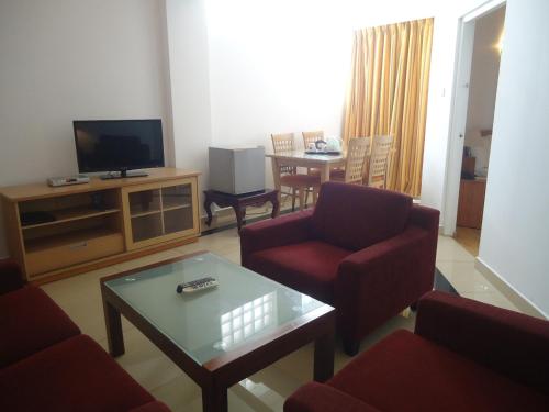 a living room with red chairs and a television at Global Towers Hotel & Apartments in Colombo