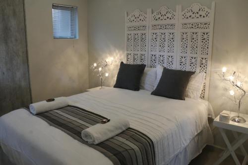 een slaapkamer met een groot wit bed met 2 lampen bij Millennium Body Guards Guesthouse in Hartbeespoort