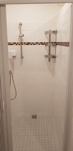 y baño de azulejos blancos con ducha y lavamanos. en Pension & Restaurace Na Rychtě en Praga