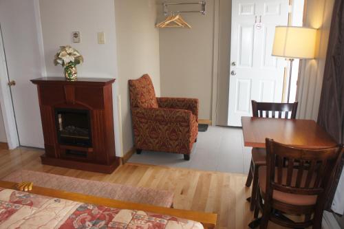 a living room with a fireplace and a table and a chair at Motel Clair Mont in Sainte-Agathe-des-Monts