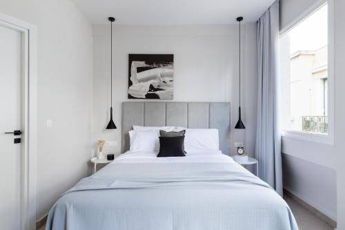 a white bedroom with a large bed and a window at Luxury Apartments in Plaka by UPSTREET in Athens