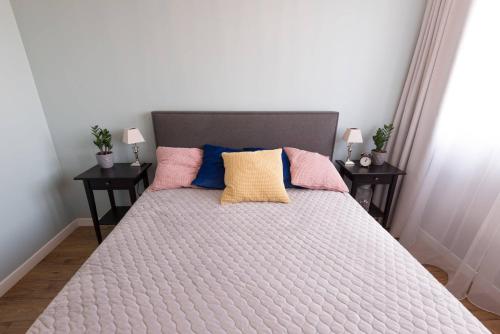 Una cama con almohadas rosas y azules. en Studzienna, en Wroclaw