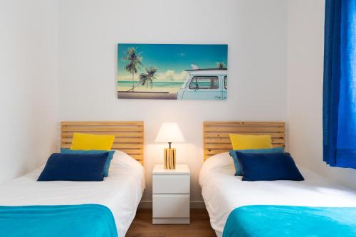Duas camas individuais num quarto com almofadas azuis e amarelas. em DELUXE HOME, SEA VIEW AND TERRACE GC52 em Arucas