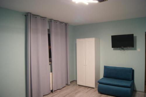 Habitación con silla azul y TV. en Villa Tymotka, en Lublin