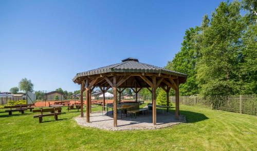 a gazebo with tables and benches in a park at Centrum Wypoczynkowo-Konferencyjne Solaris in Łazy