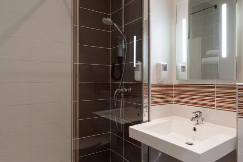 een badkamer met een wastafel en een douche bij The Originals City, Hôtel Continental, Poitiers (Inter-Hotel) in Poitiers
