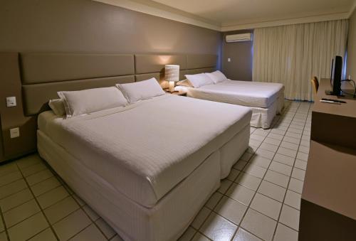 a hotel room with two beds and a television at Hardman Praia Hotel in João Pessoa