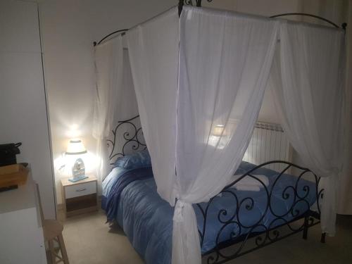 a bedroom with a canopy bed with white curtains at Bed Rho Stazione - Fiera in Rho
