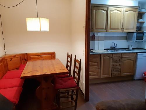 a kitchen with a wooden table and a red couch at Apartaments Can Bundanci in Setcases