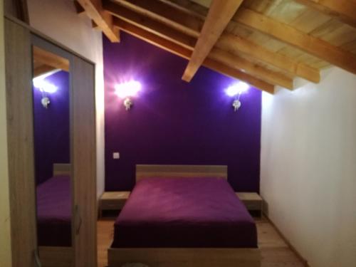 Cette chambre dispose d'un lit violet avec des lumières sur le mur. dans l'établissement Gîte de caractère en pleine nature, à Bourg-de-Visa