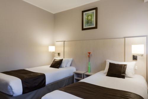 una habitación de hotel con 2 camas y un jarrón de flores en The Originals Access, Hôtel La Dousseine, Dreux Nord (Inter-Hotel), en Anet