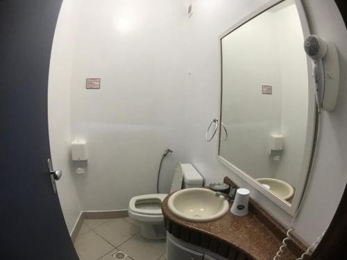 a bathroom with a sink and a toilet and a mirror at GH Bizkaia in Florianópolis