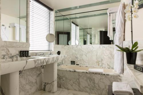 a bathroom with a tub and a sink and a mirror at Hotel Square in Paris