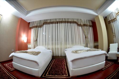 two beds in a room with red walls at Hotel New Star in Skopje