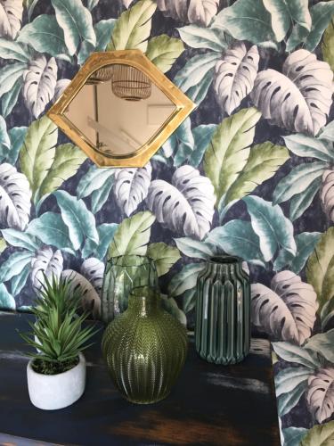 a mirror and vases on a table with a wallpaper at Ca Sa Padrina in Sóller