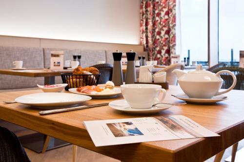 uma mesa de madeira com chávenas de chá e pratos em Upstalsboom Wyk auf Föhr em Wyk auf Föhr