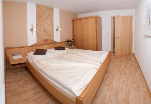 ナウダースにあるApart Sunnbichlのウッドフロアの客室で、白い大型ベッド1台が備わります。