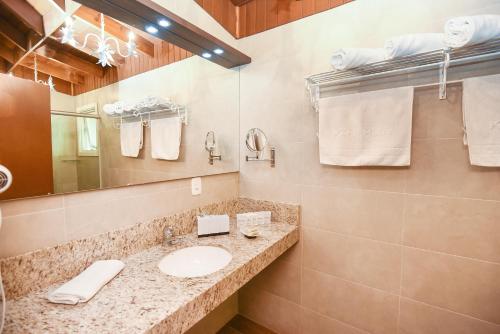 a bathroom with a sink and a mirror and towels at Hotel Kehl Haus in Gramado