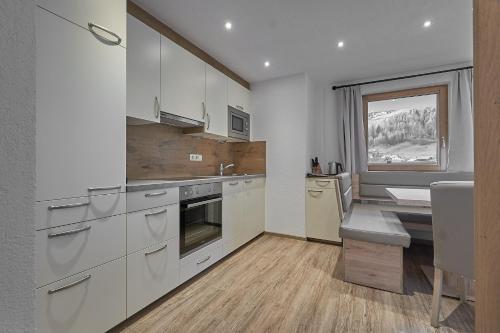 a kitchen with white cabinets and a sink and a window at Hotel Garni Schönblick in Sölden