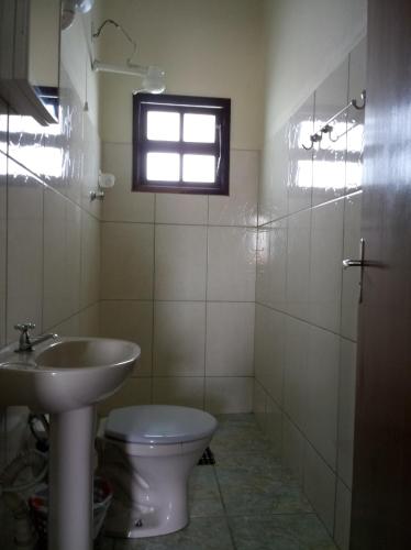 a bathroom with a toilet and a sink and a window at Apartamentos Apiaí in Ilha Comprida
