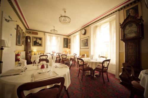 a dining room with tables and chairs and a clock at The White Hart Hotel in Hayle