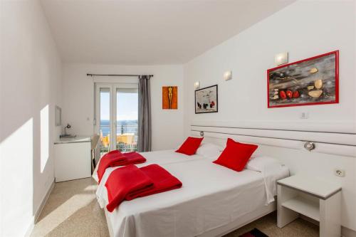 a bedroom with a large white bed with red pillows at Ark Beach Apartments in Split