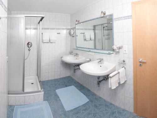 a bathroom with two sinks and a shower and a mirror at Apart Sunnbichl in Nauders
