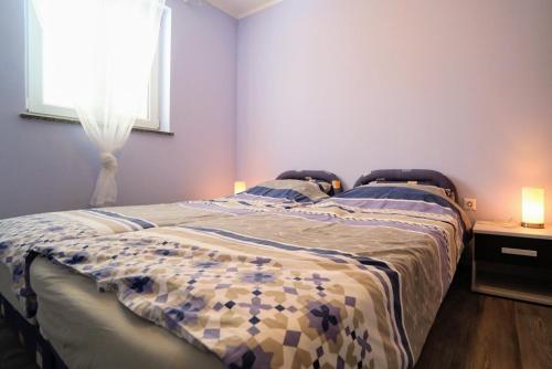 a bedroom with a bed and a window with two lamps at Apartments Kristijana in Crveni Vrh