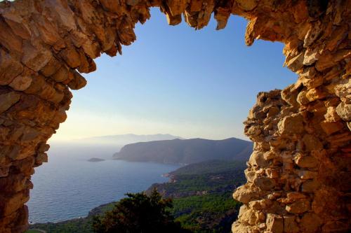 a view of the ocean through a stone window at Limeri Traditional Guest House in Monólithos